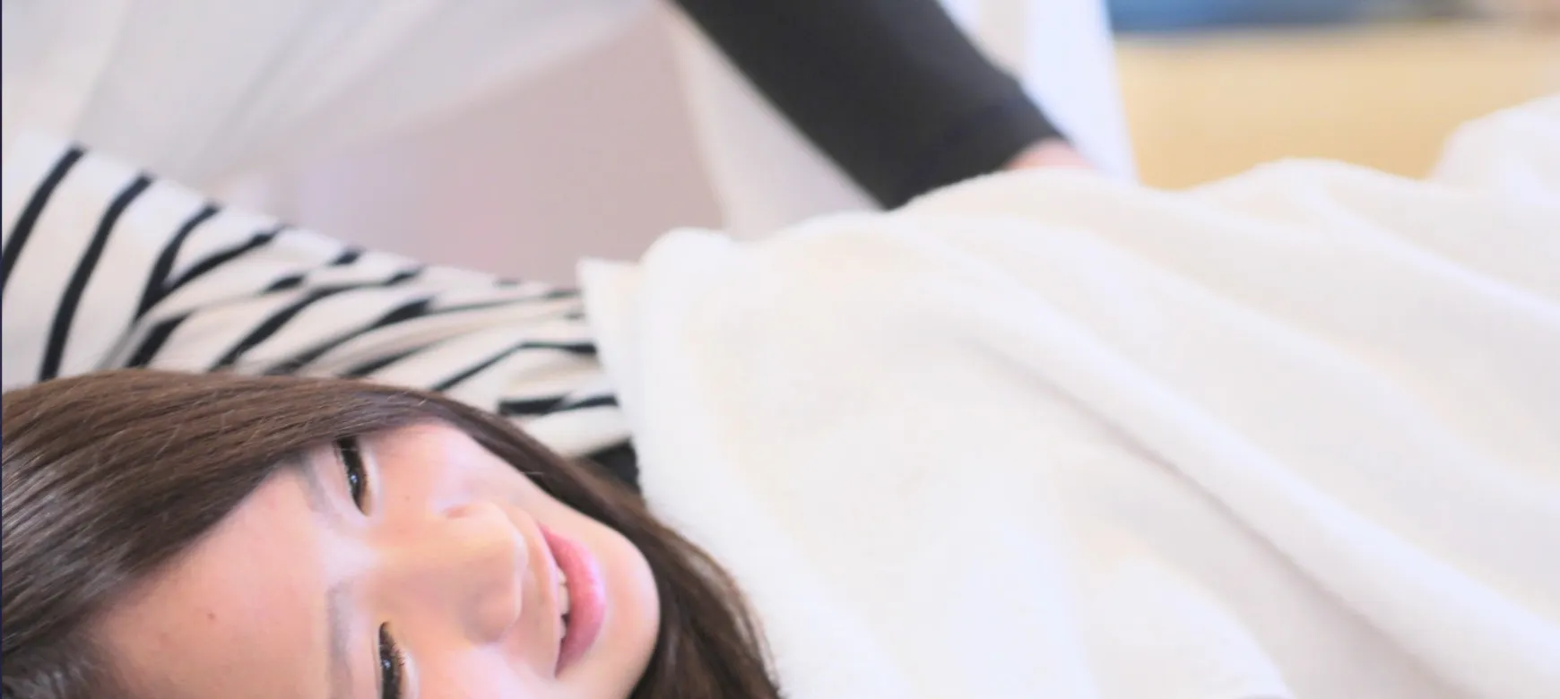 施術ベッドでリラックスした笑顔の女性｜ひまわり接骨院 整体院 瀬戸店